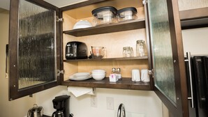 A kitchen with open cabinets, containing various kitchenware and appliances. - Candlewood Suites Ft Walton Bch - Hurlburt Area by IHG (Fort Walton Beach)