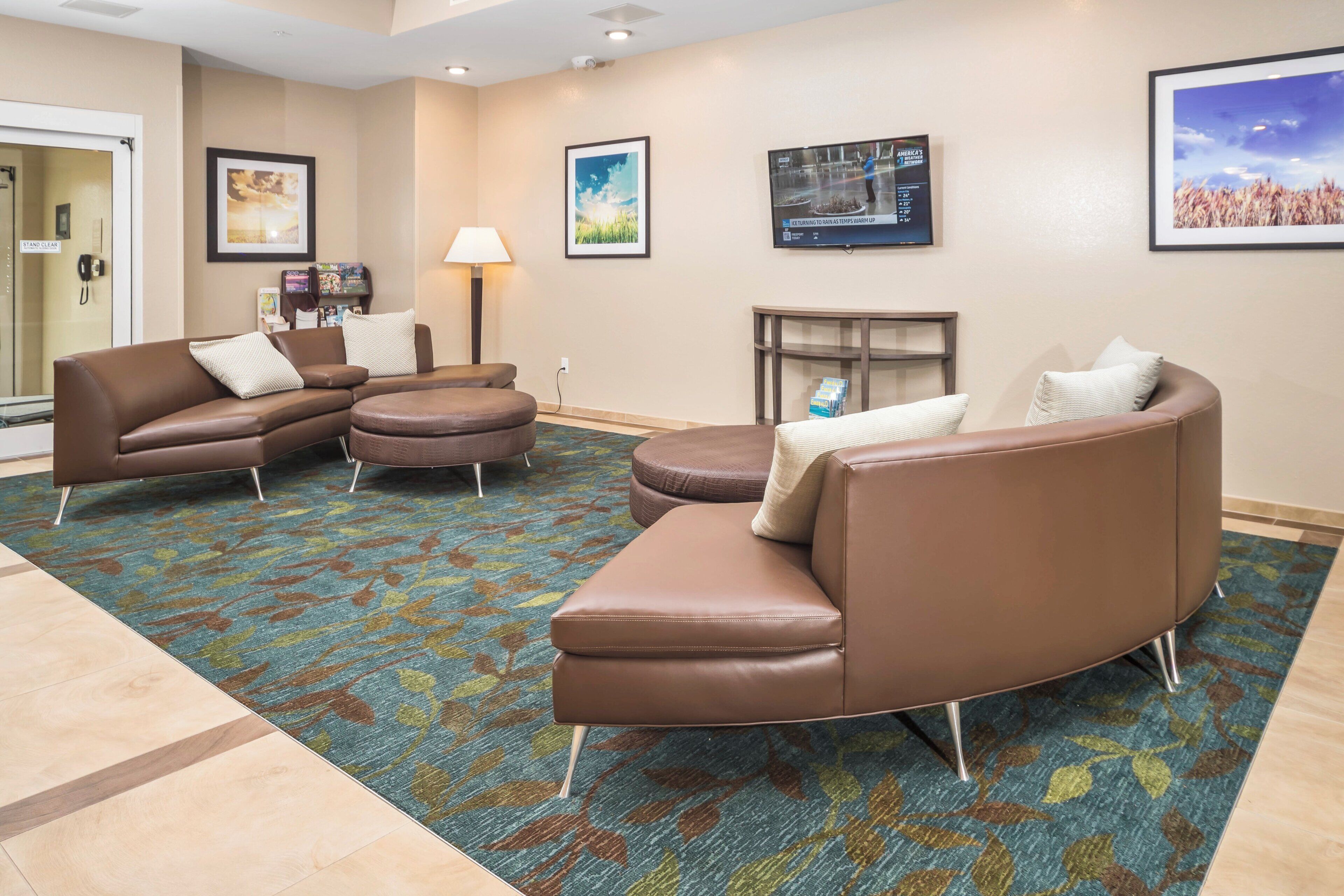 A hotel lobby with leather sofas, a patterned carpet, and framed artwork on the walls.