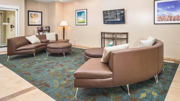 A hotel lobby with leather sofas, a patterned carpet, and framed artwork on the walls.