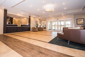 A hotel lobby with a reception desk, seating area, and a glass door entrance. - Candlewood Suites Ft Walton Bch - Hurlburt Area by IHG (Fort Walton Beach)
