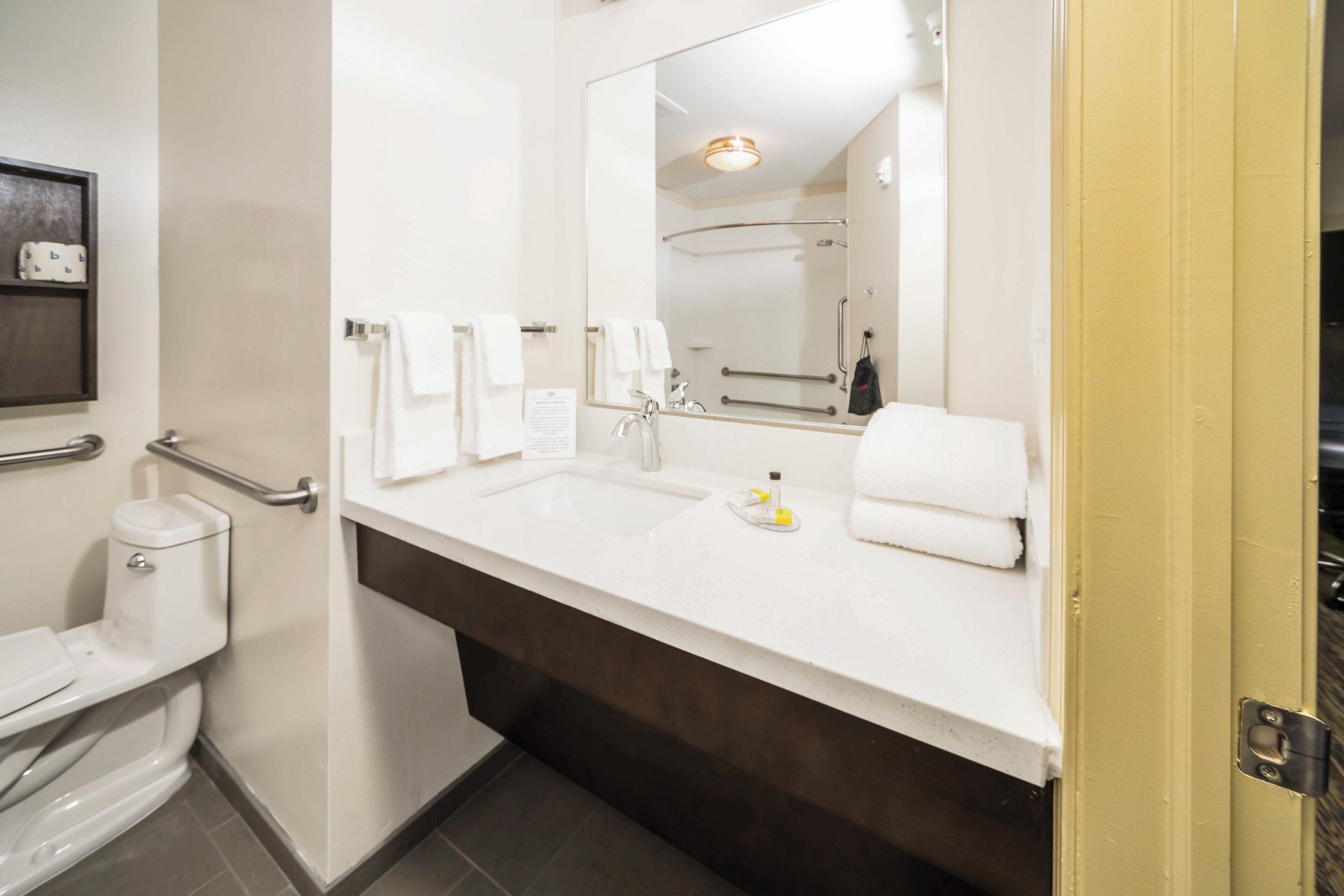 A modern bathroom with a white sink, a mirror, and a toilet.