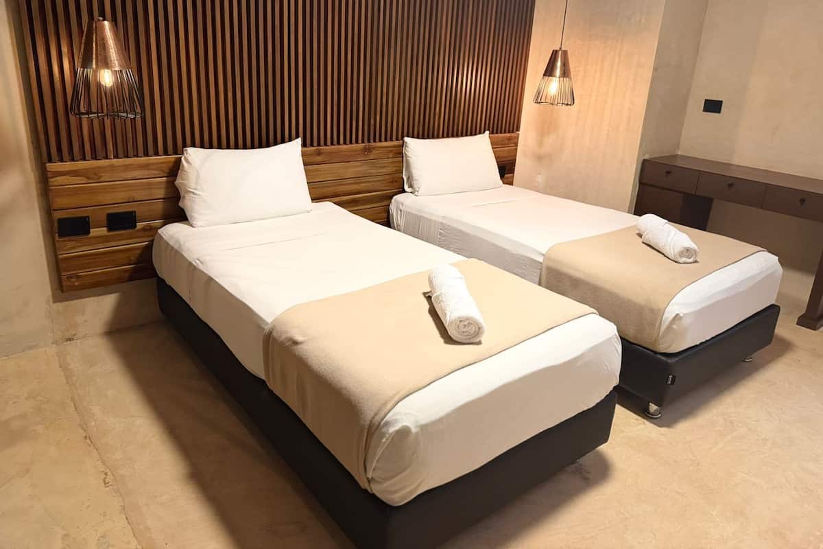 Ein Hotelzimmer mit zwei Betten, Holz-Kopfteilen und einer Wand aus Holzlatten.