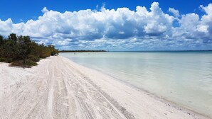 Una playa arenosa con cielo despejado y mar tranquilo.
