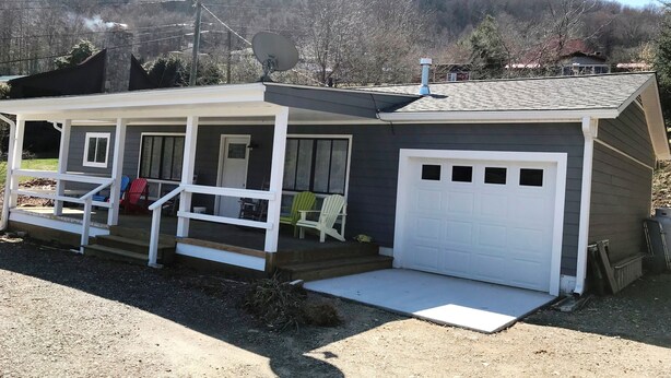 A small, single-story house with a porch, a garage, and a satellite dish.