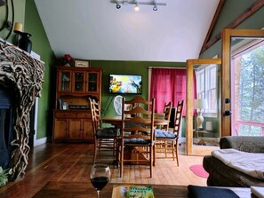 A cozy room with a dining table, chairs, a TV, and a window with curtains.