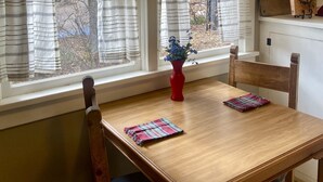 A dining area with a wooden table, chairs, and a window with striped curtains.