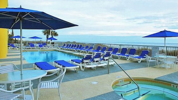 A pool area with lounge chairs and umbrellas, a pool, and a view of the ocean. - Oceanfront  Seaside Resort 1403 3BR/3BA. Resort Amenities with Amazing views (NO. MYRTLE BEACH)