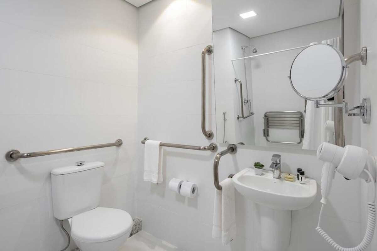 Een moderne badkamer met toilet, bidet, wastafel en handdroger.