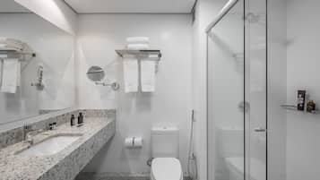 Un baño moderno con lavamanos de mármol, inodoro, ducha con mampara de vidrio y espejo.