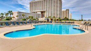 Un hôtel doté d’une piscine, de chaises longues et d’un grand bâtiment à plusieurs étages.
