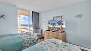 Une chambre d’hôtel avec deux lits, une télévision, une commode et une vue sur l’océan.