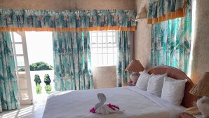 Ein geräumiges Schlafzimmer mit einem großen Bett, einem Holznachttisch und Blick ins Freie.