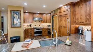 A modern kitchen with wooden cabinets, stainless steel appliances, and a granite countertop.