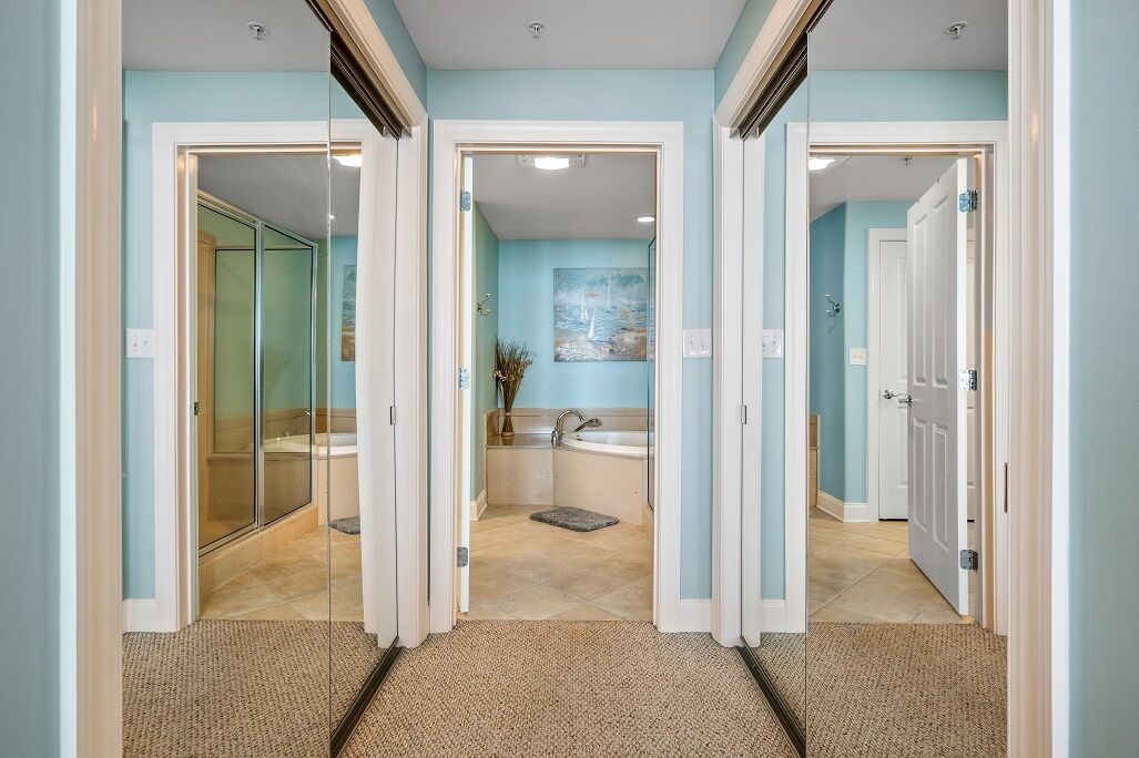Un couloir mène à une salle de bain équipée d’une douche en verre, d’une baignoire et de toilettes.