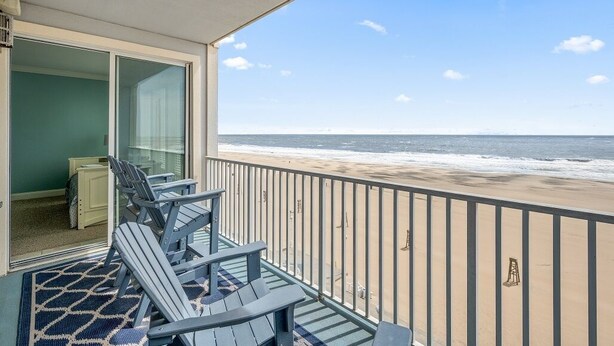 A balcony with a view of the beach and ocean.
