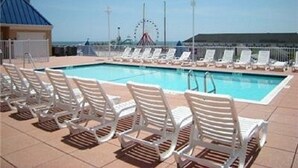 A pool area with white lounge chairs and a Ferris wheel in the background.