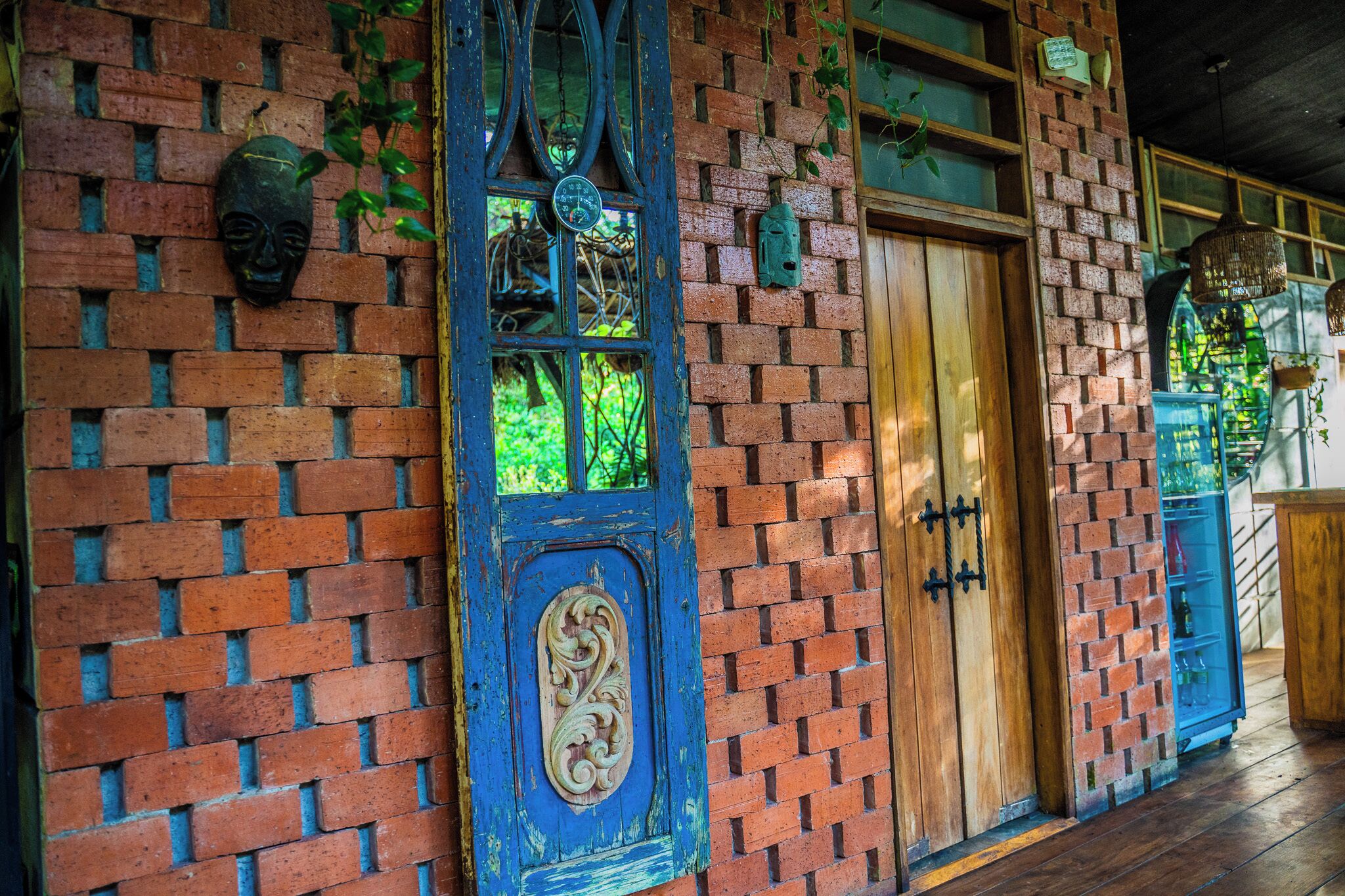 Un edificio rústico con paredes de ladrillo, puertas de madera y detalles decorativos como máscaras y un reloj.
