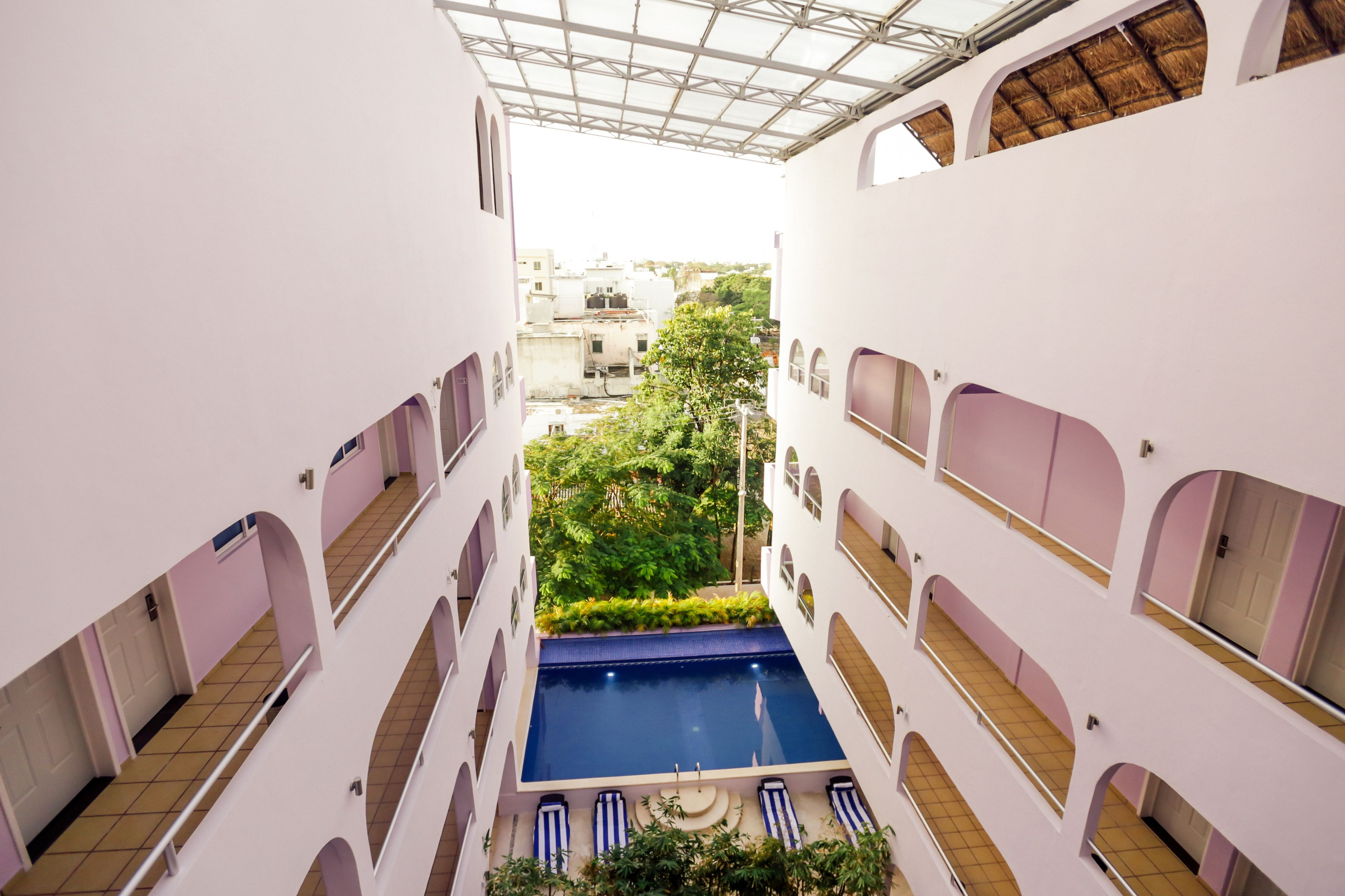 A multi-level building with a central courtyard featuring a swimming pool, surrounded by balconies and vegetation.