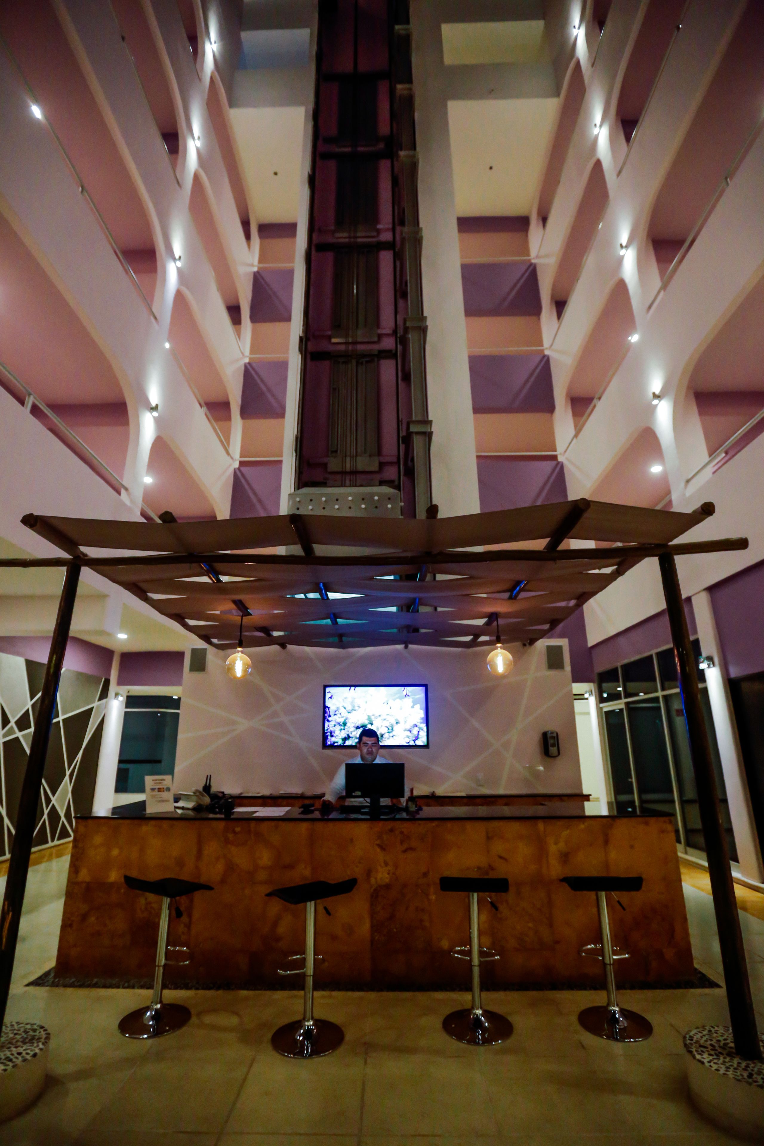 A bar area with a high ceiling, multiple levels, and a central television screen.