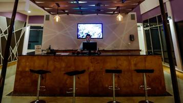 A bar area with a high ceiling, multiple levels, and a central television screen.