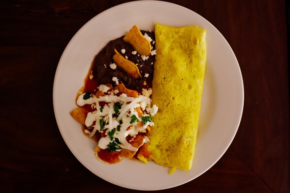 Un plato con un crepé, frijoles y una cobertura de crema agria y hierbas.