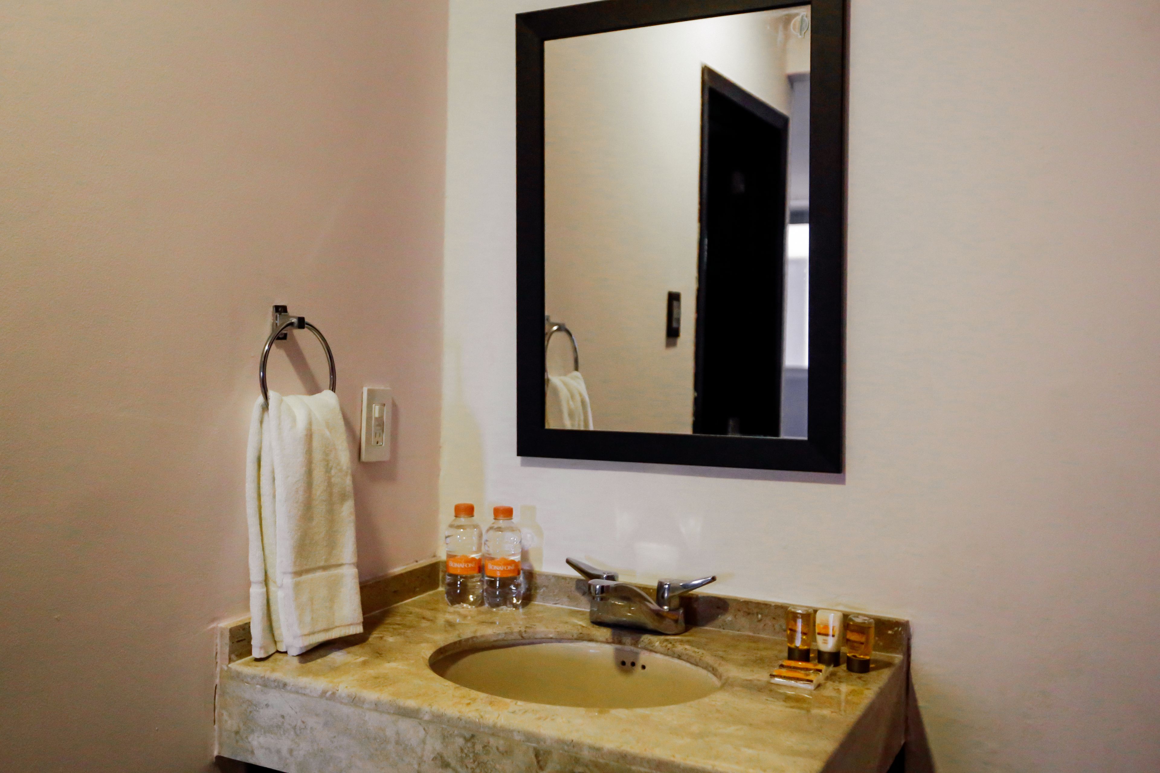 A bathroom with a marble sink, a towel hanging on a rack, and a mirror above the sink.