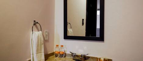 A bathroom with a marble sink, a towel hanging on a rack, and a mirror above the sink.