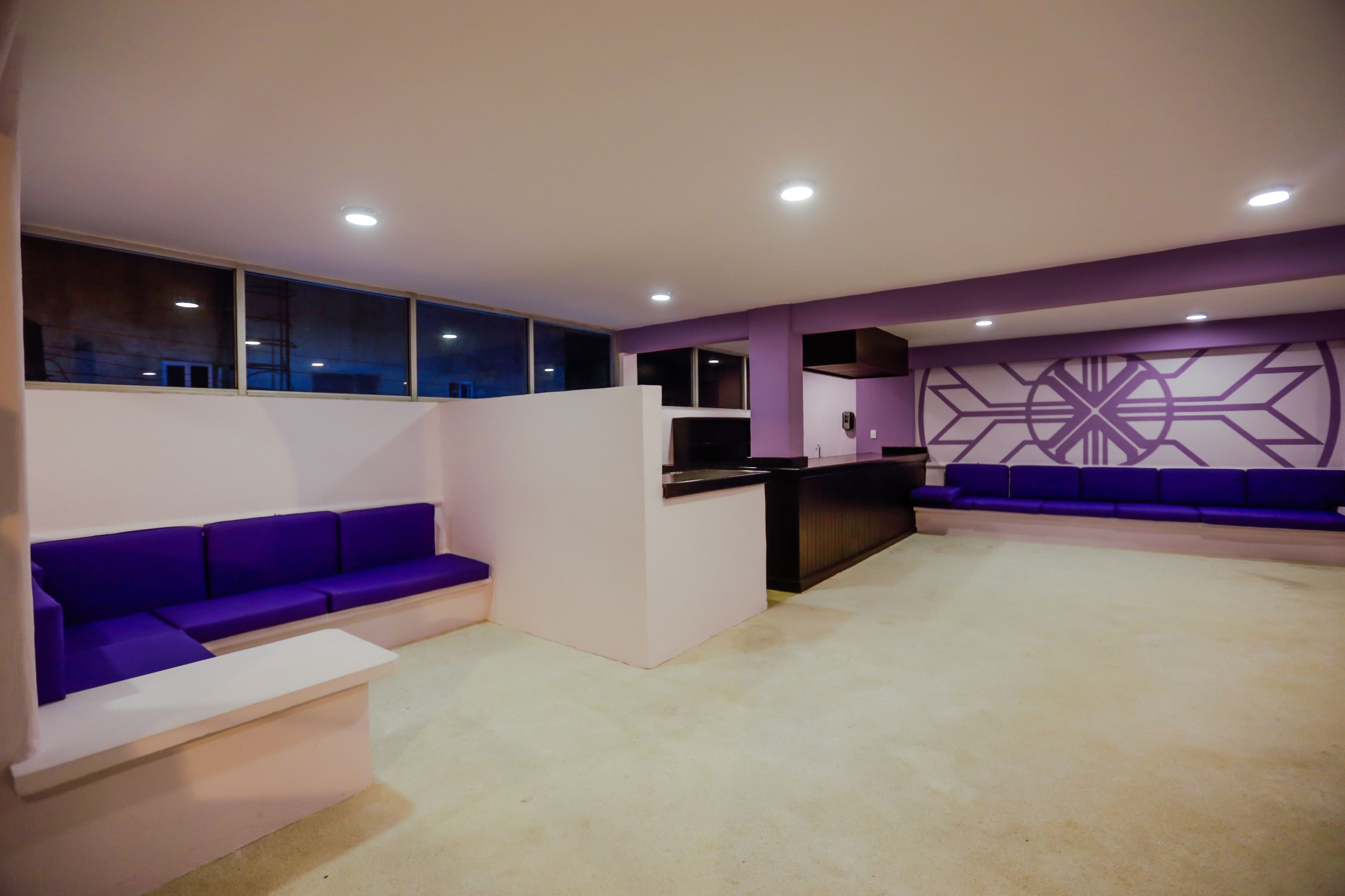 A modern lobby with purple seating, a reception desk, and a geometric wall design.