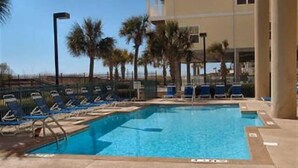 A swimming pool with lounge chairs and palm trees. - Verandas 305- Oceanfront 3BR Condo-Oceanfront Pool- Walk to Main Street (NO. MYRTLE BEACH)