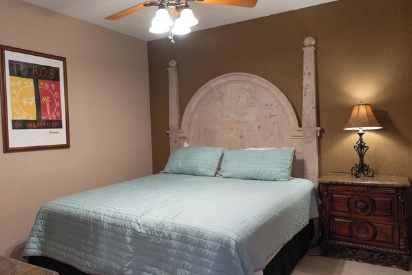 A bedroom with a bed, a nightstand, a lamp, and a framed artwork on the wall.