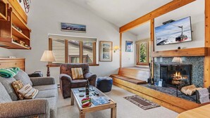 Una sala de estar acogedora con chimenea, un sofá, un sillón y una mesa de centro.