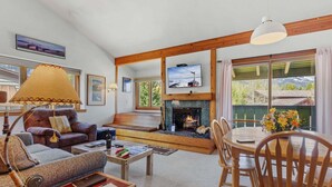 Una sala de estar acogedora con chimenea, asientos cómodos, televisor y comedor con mesa y sillas.