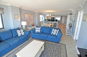 Un salon avec deux canapés bleus, une table basse blanche et un tapis à motifs.