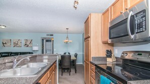 A kitchen with granite countertops, stainless steel appliances, wooden cabinets, and a dining area with a table and chairs. - Lake Front - 1 bedroom w/ a den 1 bath (Brandon)