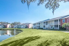 A row of townhouses with a grassy lawn and a small pond.