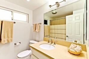 A bathroom with a white toilet, a beige sink, and a large mirror. - Beautiful Views - Sand Section of Manhattan Beach  (Manhattan Beach)