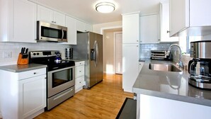 A modern kitchen with white cabinets, stainless steel appliances, and a wooden floor. - Beautiful Views - Sand Section of Manhattan Beach  (Manhattan Beach)