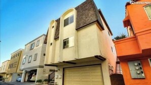 A row of modern two-story houses with beige and orange exteriors, garage doors, and a clear blue sky. - Beautiful Views - Sand Section of Manhattan Beach  (Manhattan Beach)