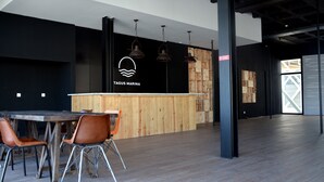 Een modern interieur met een houten receptiebalie, metalen stoelen en hanglampen.