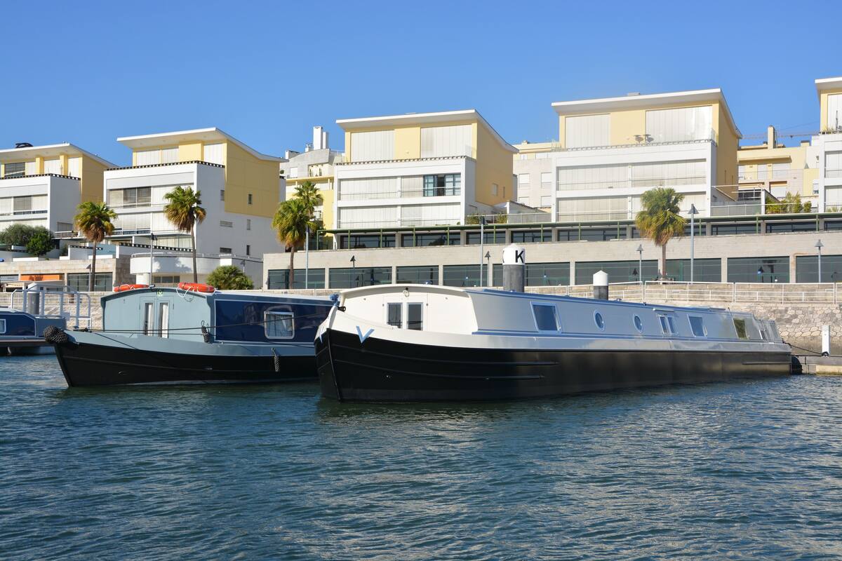 Dos barcos amarrados en un puerto deportivo con edificios al fondo.