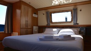 Een slaapkamer met een groot bed, houten kasten, een raam met gordijnen en een hoofdbord met een decoratief patroon.