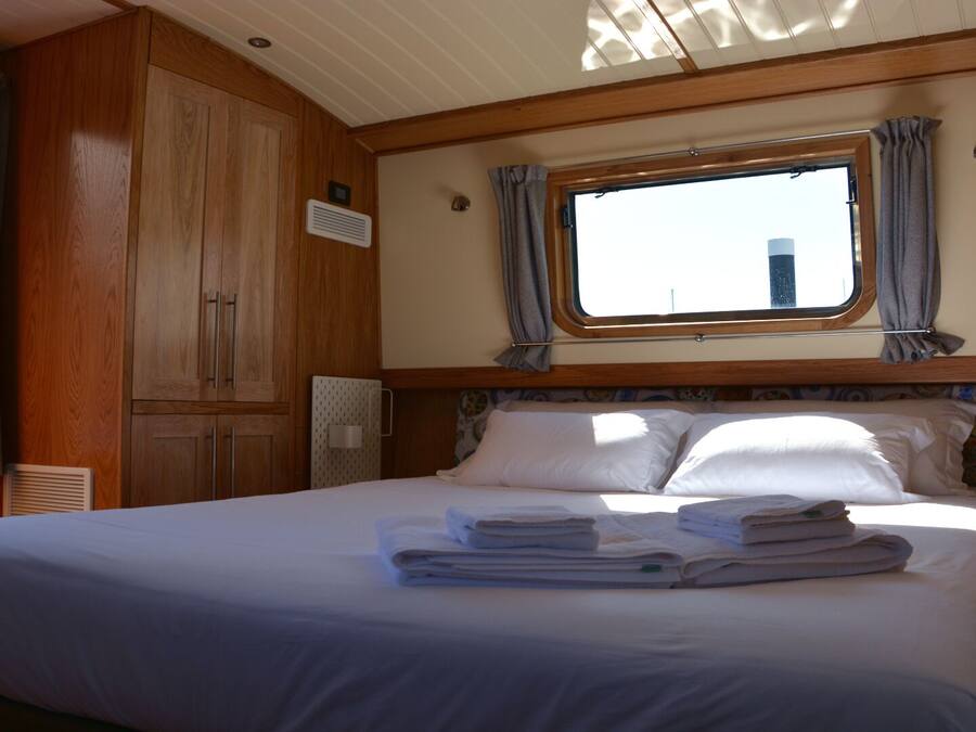 A bedroom with a large bed, wooden cabinets, a window with curtains, and a headboard with a decorative pattern.