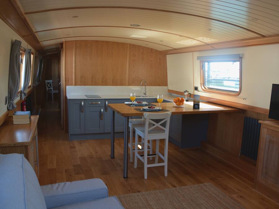 A compact kitchen with wooden cabinets, a dining table, and a TV.