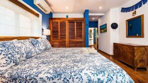 Un dormitorio con una cama grande, un armario de madera y un ventilador de techo.