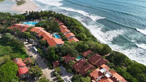 Vista aérea de una propiedad costera con varias construcciones, una piscina y una playa.