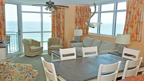 A room with a dining table, chairs, a sofa, and a view of the ocean. - Oceanfront 3BR/3B Lockout. Resort Amenities, Pools, Lazy River, Kiddie Pool (NO. MYRTLE BEACH)