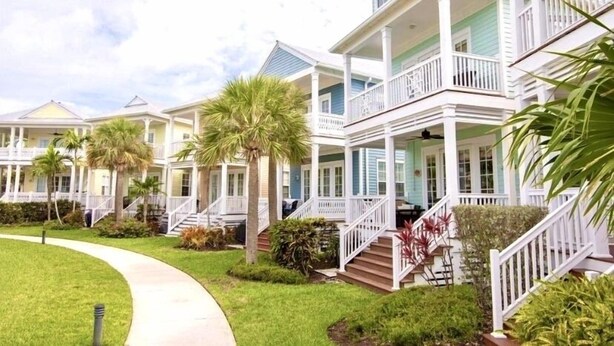 A row of coastal-style houses with white railings and green roofs, connected by a pathway. - Islamorada Anglers Reef! “Sandbar Bungalow Villa" AMAZING! Middle row location!  (Islamorada)