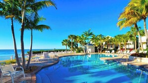 A swimming pool with lounge chairs and palm trees, overlooking the ocean. - Islamorada Anglers Reef! “Sandbar Bungalow Villa" AMAZING! Middle row location!  (Islamorada)