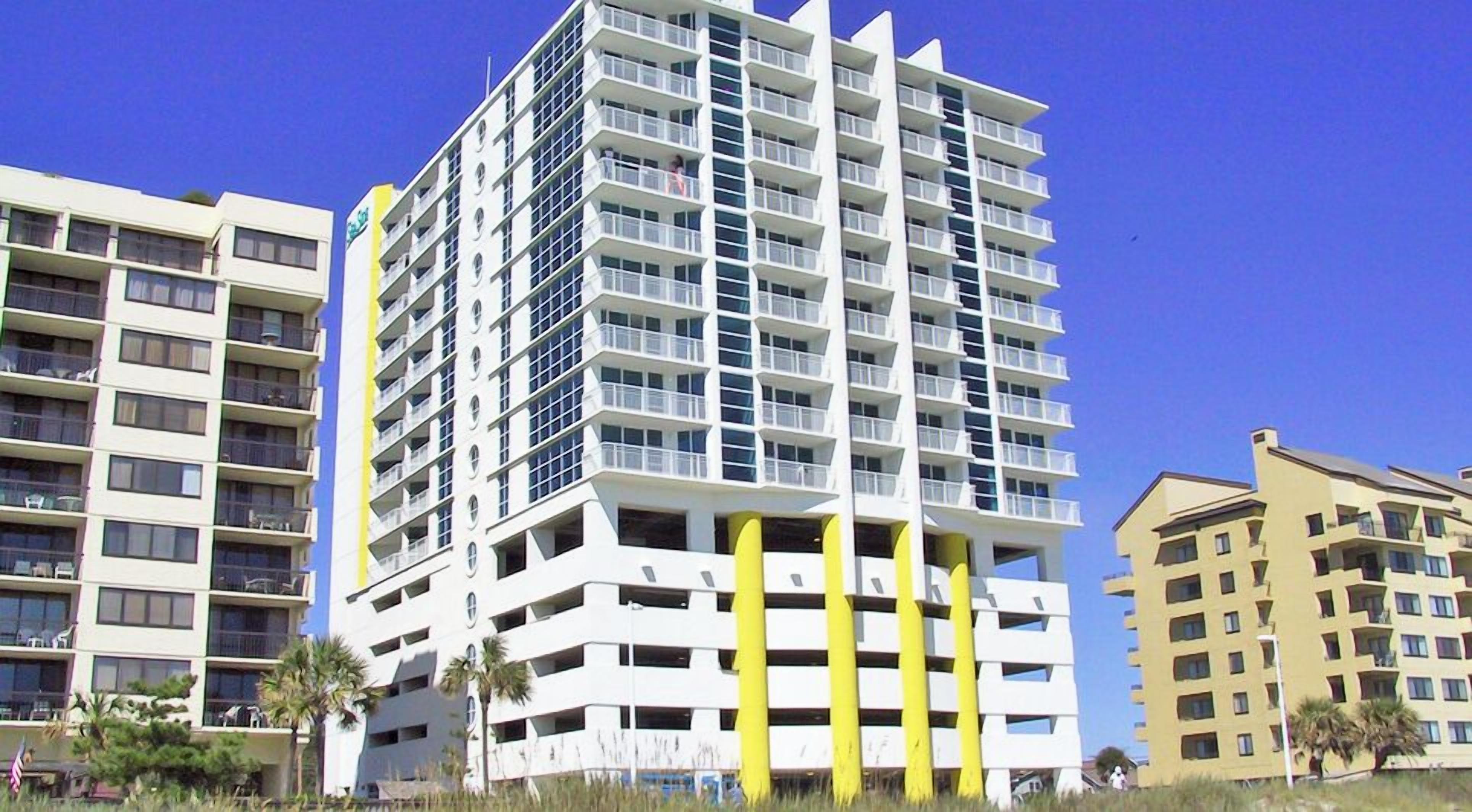 A multi-story hotel with balconies, a flat facade, and a clear sky.