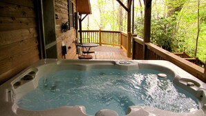 Un bain à remous sur une terrasse en bois, avec vue sur une forêt.